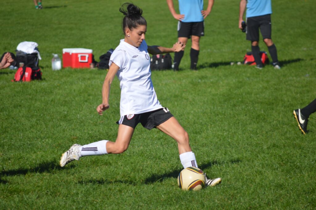 A woman kicking a soccer ball on a soccer field